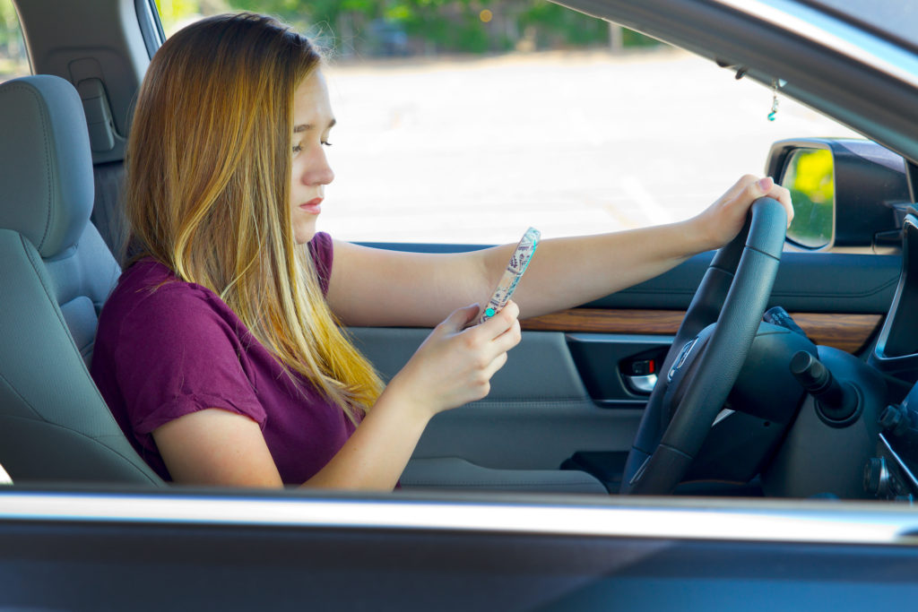 Teens and texting while Driving. British teen texting while Driving. Girl jumping on the Seat while Driving over Bumps. Texting while Driving is illegal in 47 States of the USA.