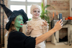 Mother in witch attire making selfie with her son in zombie costume