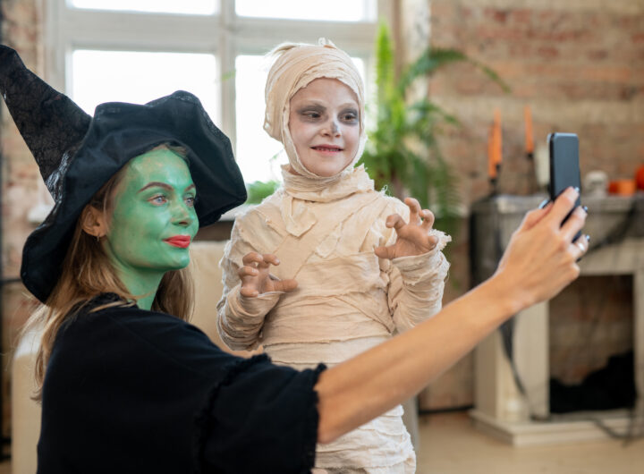 Mother in witch attire making selfie with her son in zombie costume
